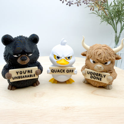 Three animal figurines holding signs with humorous text on a wooden surface.