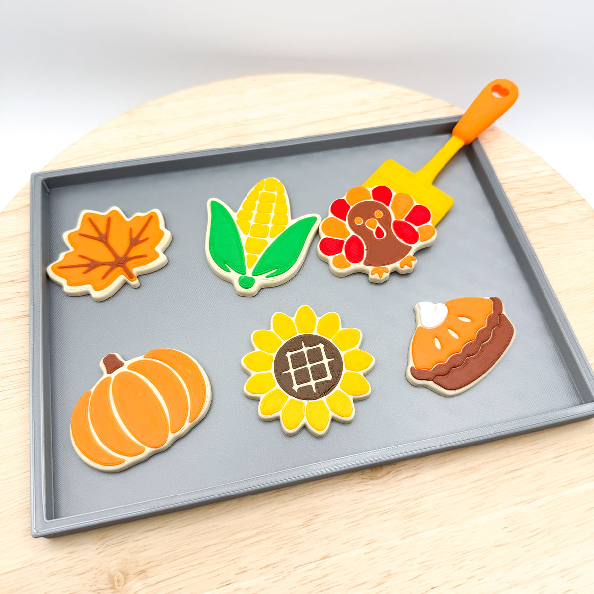 Fall cookie tray set on a wood board, spatula tucked behind the turkey cookie